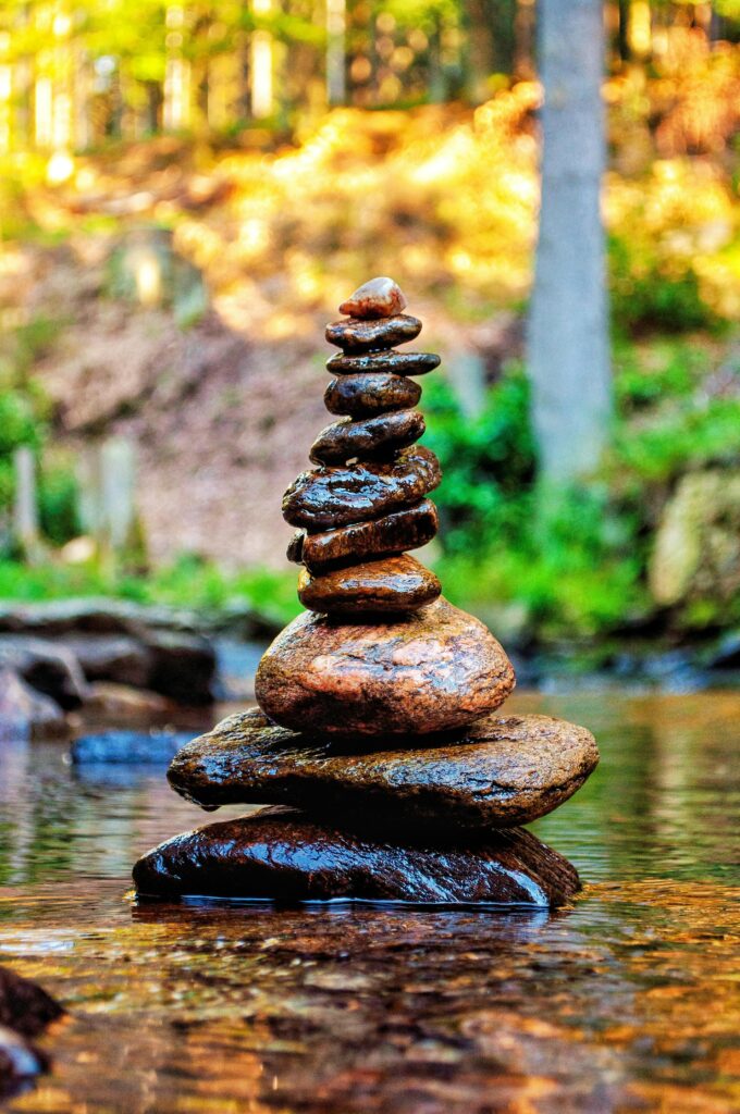 Meditative stone stack in serene forest stream, embodying nature and tranquility.